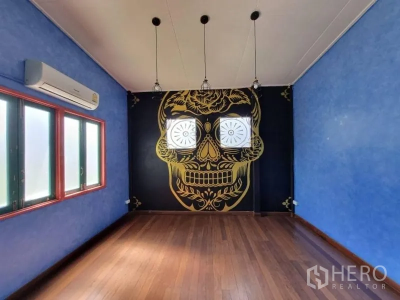 Detached House for rent in Khlong Toei, Bangkok - Feature room with large gold skull mural, wood floor and pendant lights.