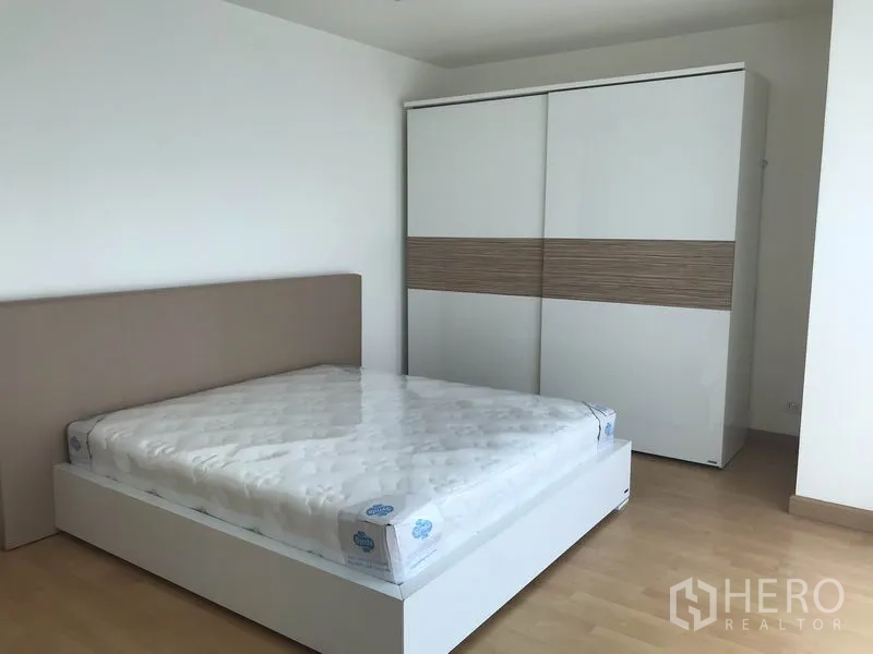 Condominium for rent in Khlong Toei, Bangkok - Bedroom with sliding-door wardrobe and upholstered headboard.