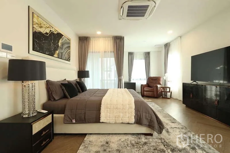 Detached House for rent in Saphan Sung, Bangkok - Master bedroom view toward the TV wall with recliner seating by the windows.