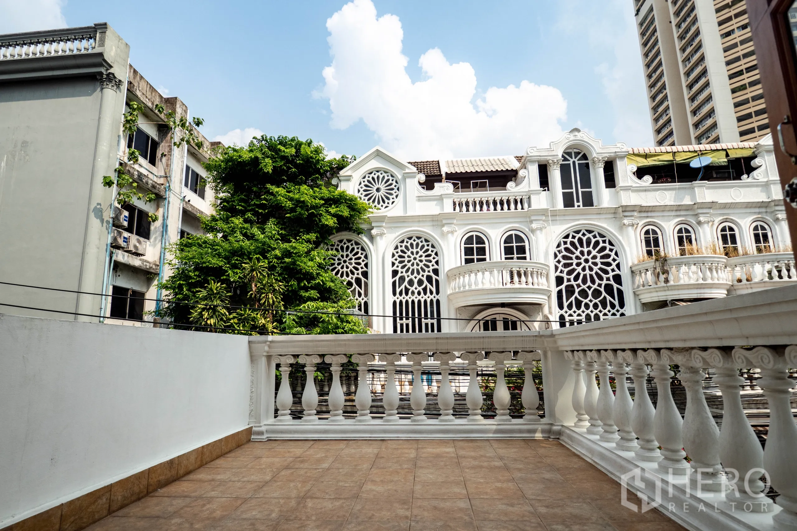 Townhouse for rent in Khlong Toei, Bangkok - Balcony terrace with white balustrade overlooking decorative white townhouses.