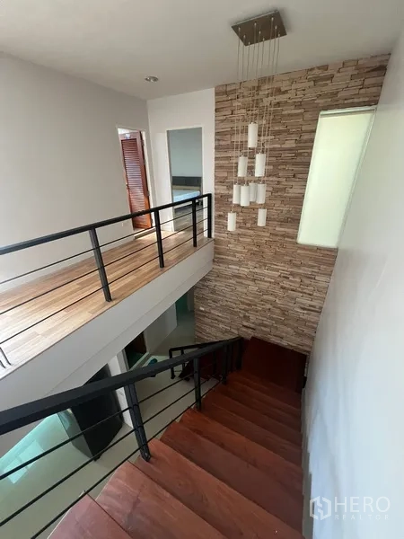Townhouse for rent in Din Daeng, Bangkok - Staircase with wooden steps, metal railing and stone accent wall with pendant lighting.