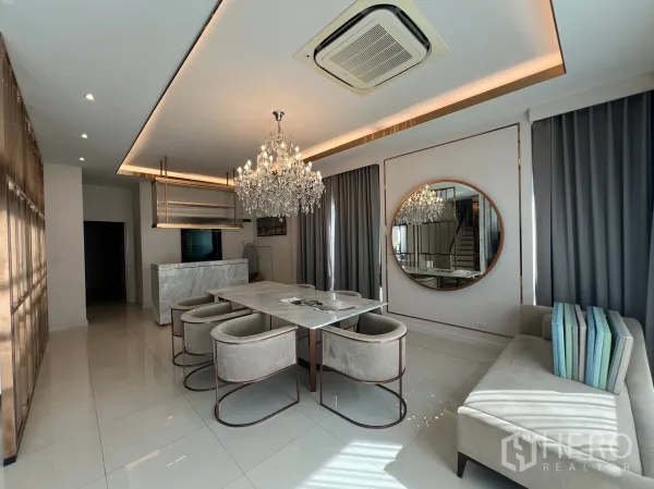 Detached House for rent or sale in Prawet, Bangkok - Open dining room with crystal chandeliers, marble island and gray drapes.