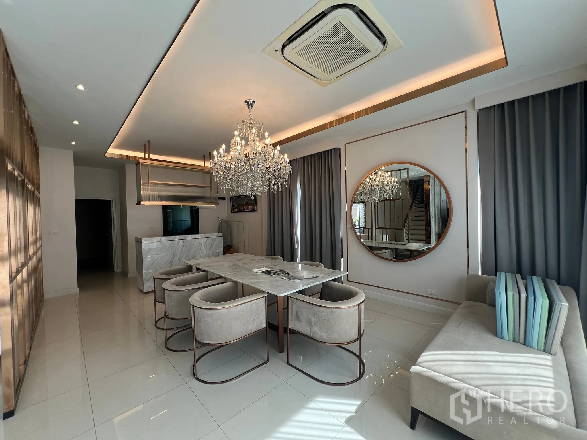 Detached House for rent or sale in Prawet, Bangkok - Open dining room with crystal chandeliers, marble island and gray drapes.