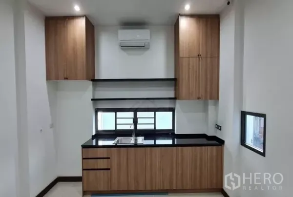 带办公室的家 出租在Watthana, Bangkok - 次级茶水间，木柜与黑色操作台，窗前水槽，壁挂空调