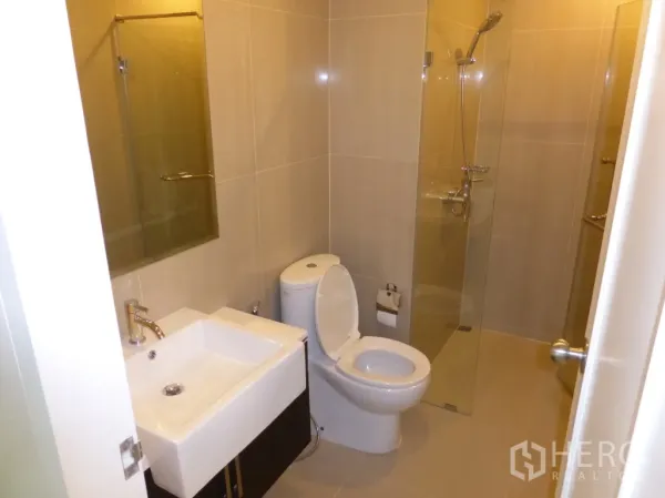 公寓 出租或出售在Ratchathewi, Bangkok - 现代浴室，方形洗手台、坐便器与玻璃淋浴间。