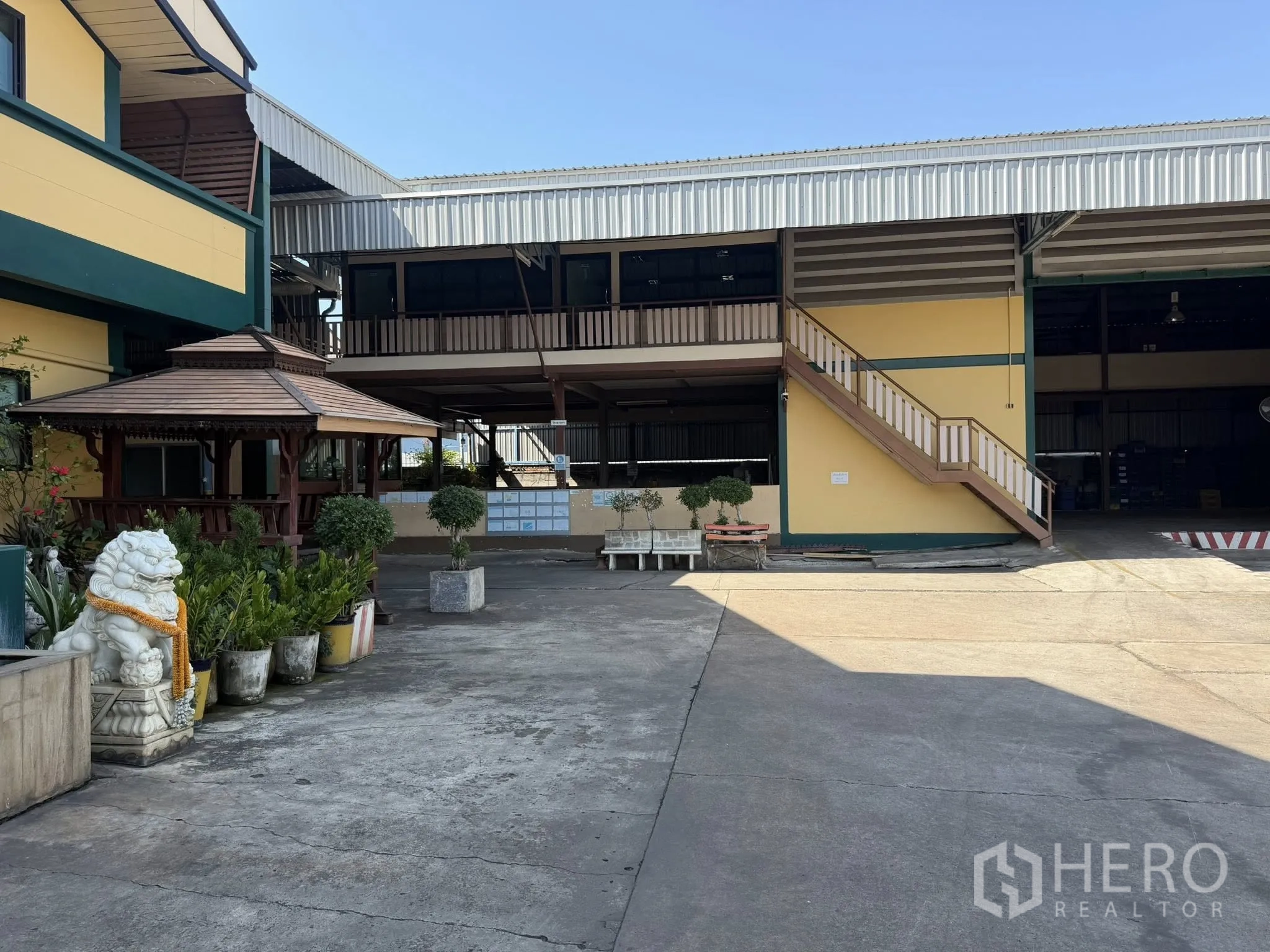 Factory for rent in Bang Phli, Samut Prakan - Courtyard of Bang Phli factory with yellow office wing, external staircase and wooden gazebo.