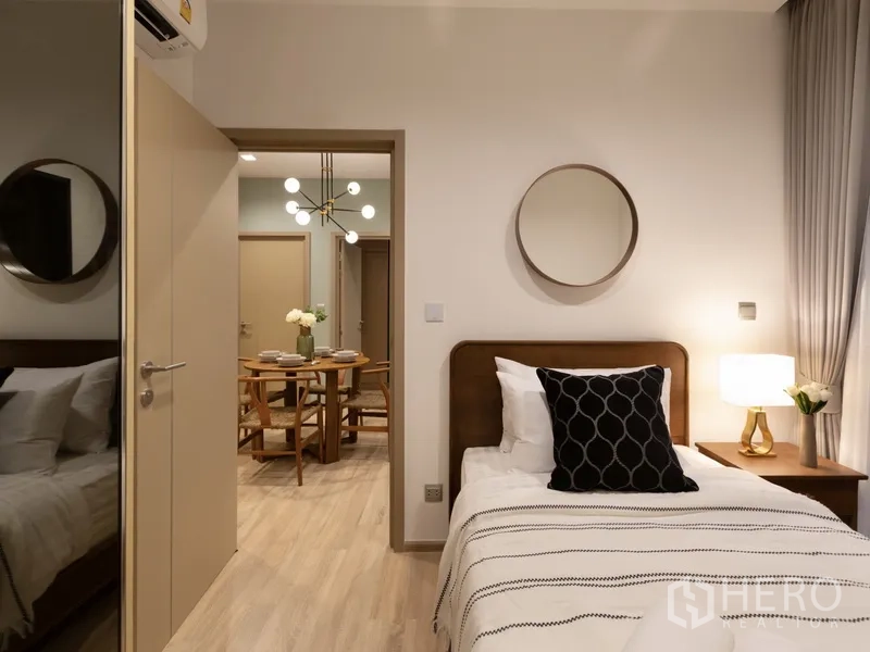 Condominium for rent or sale in Watthana, Bangkok - Cozy second bedroom with single bed, side lamp and view toward the dining area.