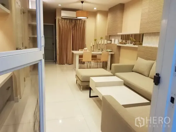 联排别墅 出租在Phra Khanong, Bangkok - 开放式客餐厅，米色调装修，转角沙发与白色地砖