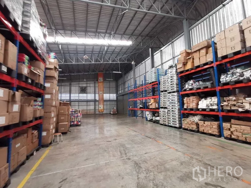 Warehouse for rent or sale in Nonthaburi - High-bay warehouse aisle with pallet racking and concrete floor for forklifts.