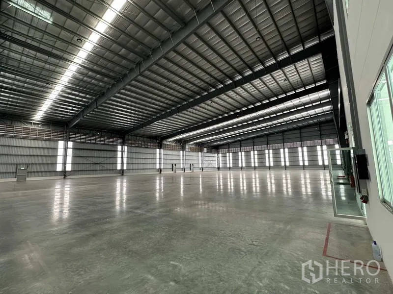 Factory for rent in Bang Sao Thong, Samut Prakan - Wide-angle view of warehouse space with steel beams and polished concrete floor.