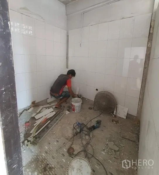 Shophouse for rent in Bangkok - Compact tiled room under renovation with white wall tiles and unfinished concrete floor.