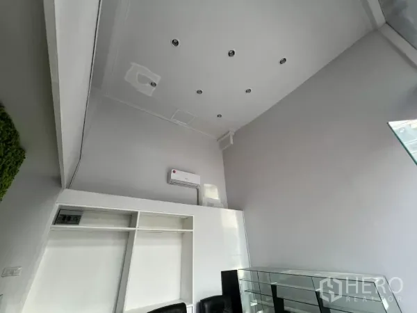 Retail Space for rent - Upward view of tall white ceiling with recessed lighting and air conditioner.