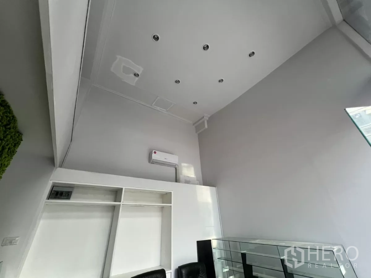 Retail Space for rent - Upward view of tall white ceiling with recessed lighting and air conditioner.