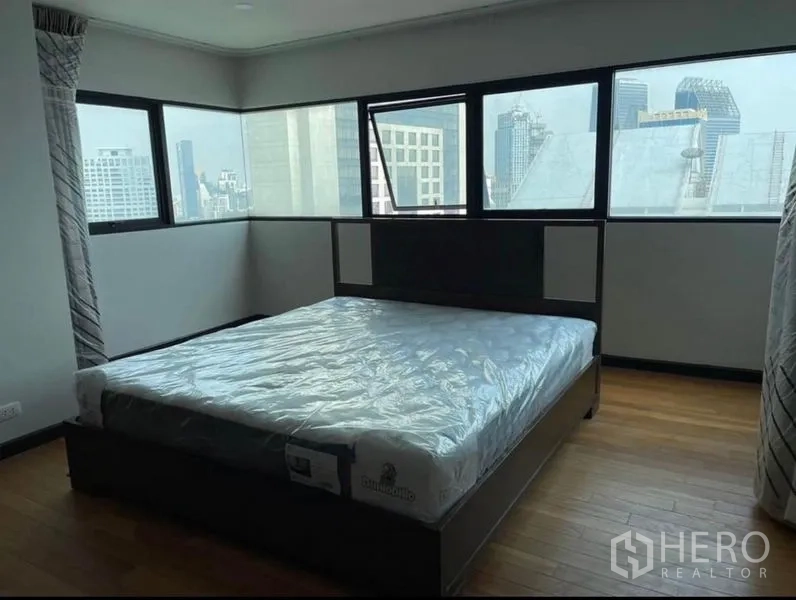 Condominium for rent - Bedroom with corner windows overlooking the Bangkok cityscape.