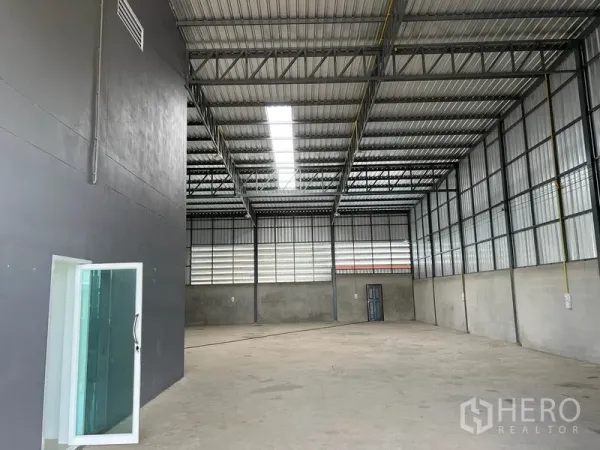Warehouse for rent in Lam Luk Ka, Pathum Thani - Spacious high-ceiling warehouse hall with steel trusses and skylight panels.