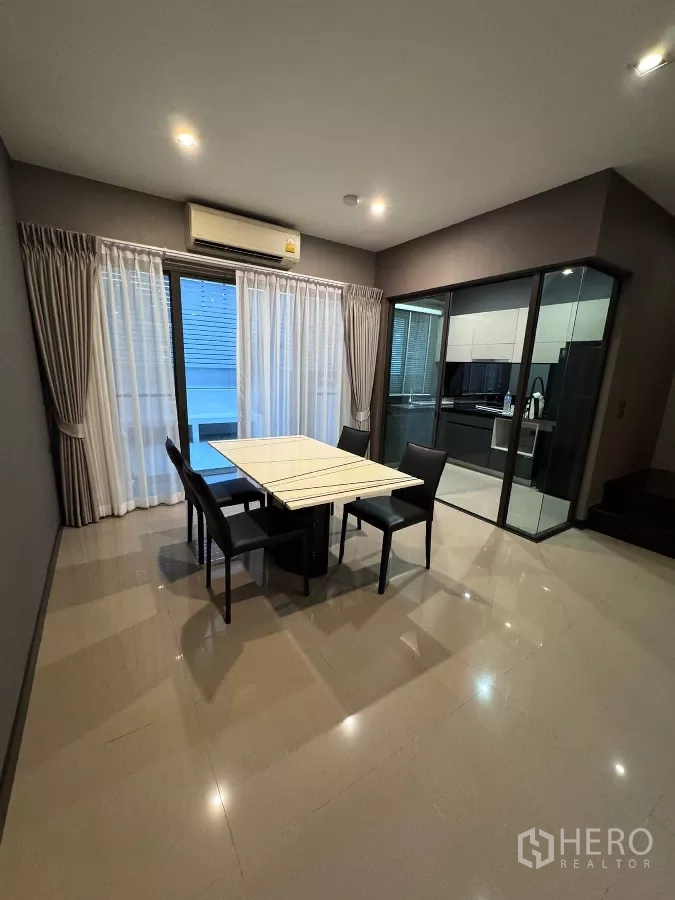 Townhouse for rent or sale in Lat Phrao, Bangkok - Dining space beside a glass-enclosed built-in kitchen.