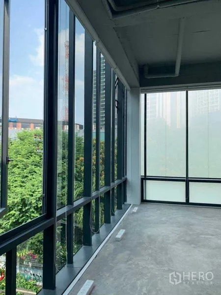 Office Space for rent in Khlong Toei, Bangkok - Bright workspace with floor-to-ceiling glass and views of trees and city buildings.