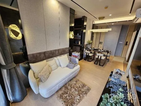 Condominium for rent - Stylish Ekkamai condo living room with cream sofa, rug and dining area, warm lighting.