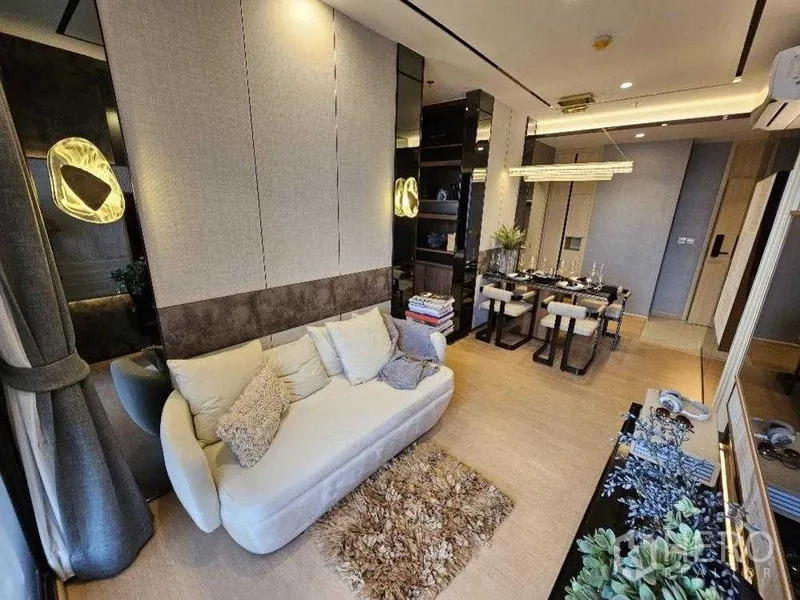 Condominium for rent - Stylish Ekkamai condo living room with cream sofa, rug and dining area, warm lighting.