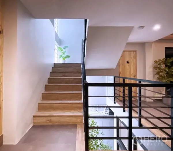 Office Space for rent in Bang Rak, Bangkok - Well-lit staircase with wooden steps and black metal railing in a modern low-rise office building.