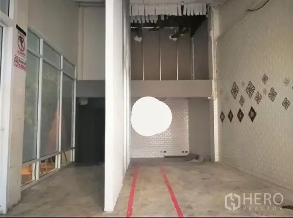 零售空间 出租在Phaya Thai, Bangkok - 挑高零售铺面，水泥地与白色砖墙，带部分夹层结构。