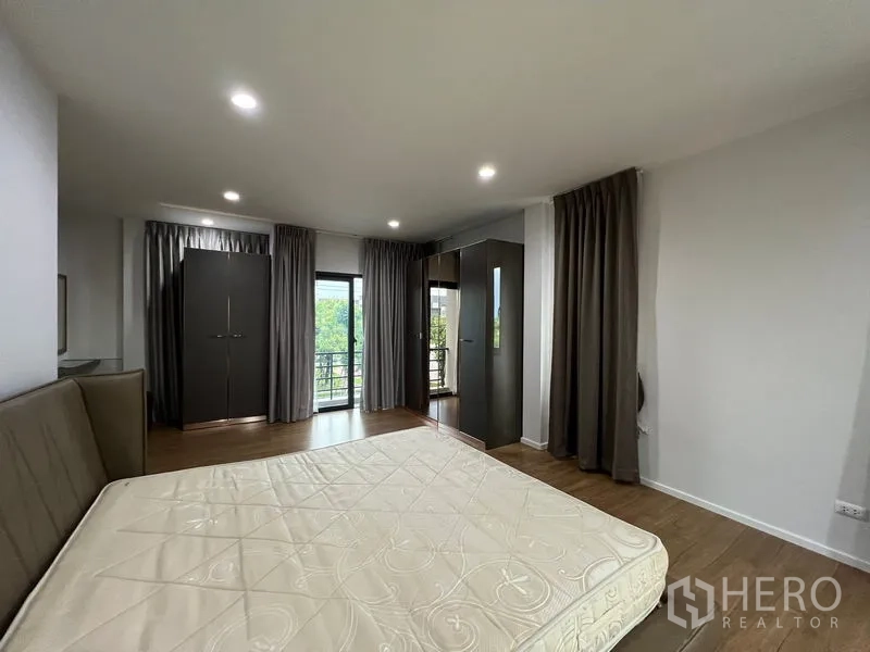 Detached House for rent in Saphan Sung, Bangkok - Master bedroom with wardrobes and sliding door opening to a balcony overlooking trees.
