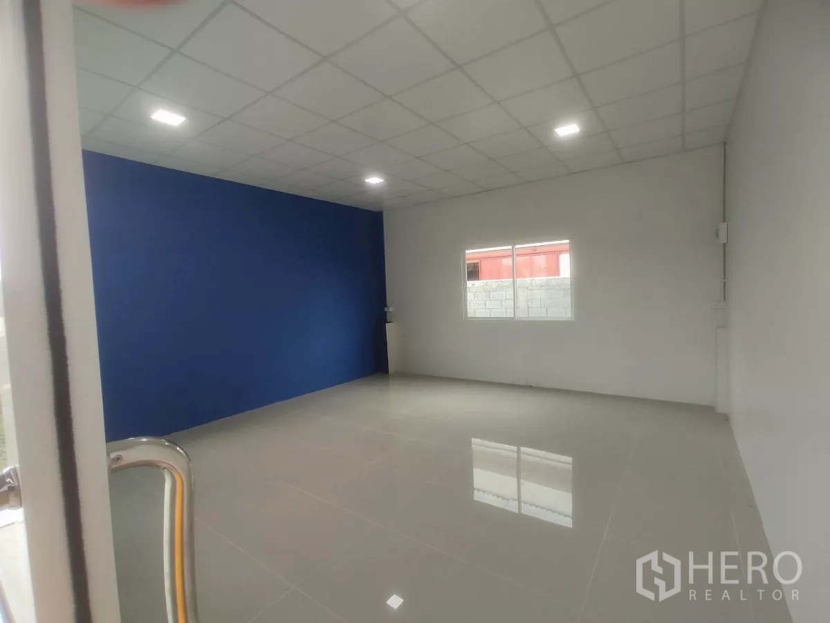 Factory for sale in Khlong Toei, Bangkok - Bright office room with blue feature wall, tiled floor and ceiling lights.