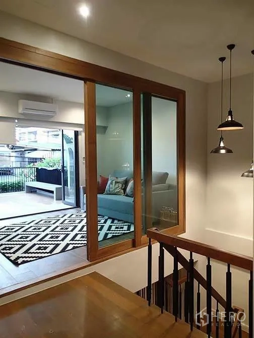 ทาวน์เฮาส์ for rent in Watthana, Bangkok - มุมมองจากบันไดไปยังพื้นที่นั่งเล่นที่มีประตูกระจกบานใหญ่และระเบียง