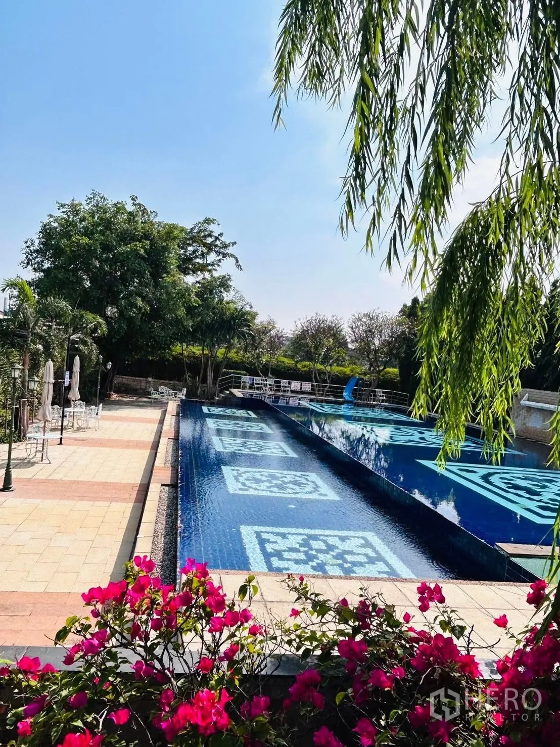 Detached House for rent in Lat Krabang, Bangkok - Community swimming pool with patterned blue tiles, deck seating and bougainvillea.