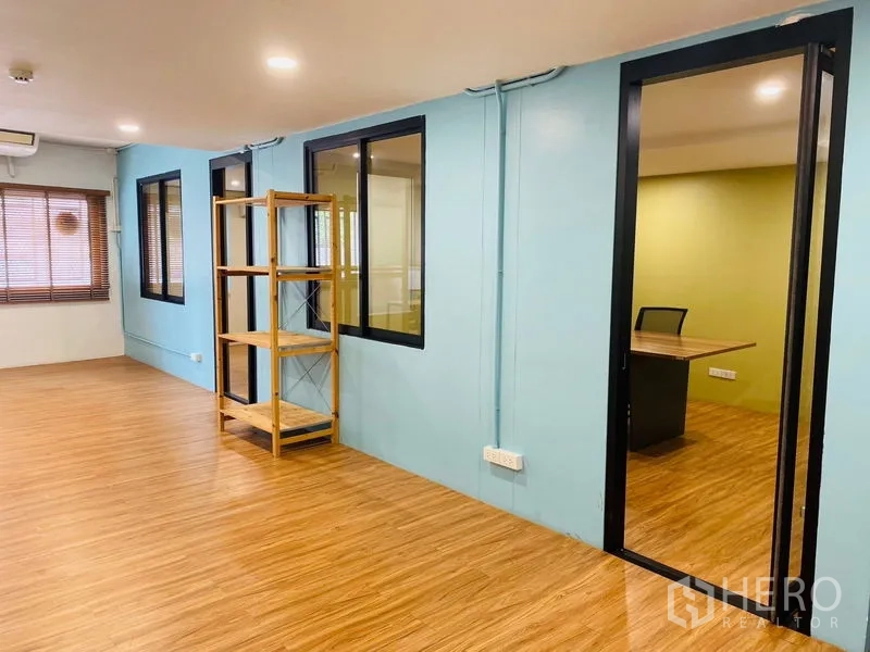 Office Space for rent in Bang Rak, Bangkok - Open area with blue accent walls, shelving unit and access to the meeting room.