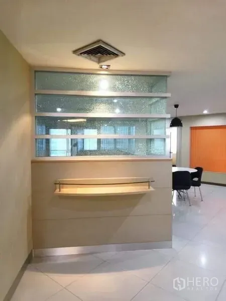 Office Space for rent - Reception nook with textured glass partition, display shelf and ceiling spotlight leading to meeting area.