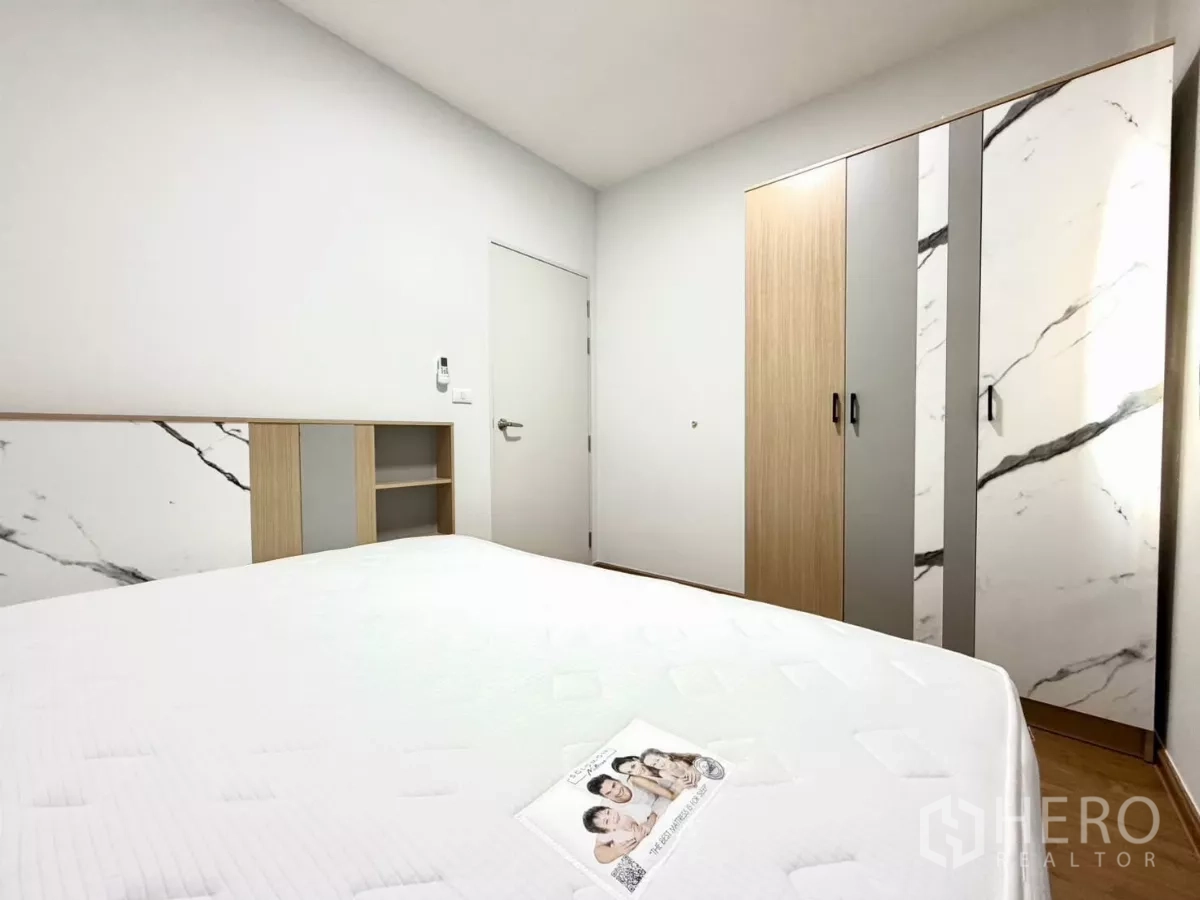 Townhouse for rent in Bang Phli, Samut Prakan - Bedroom featuring marble-pattern wardrobe and headboard shelving.