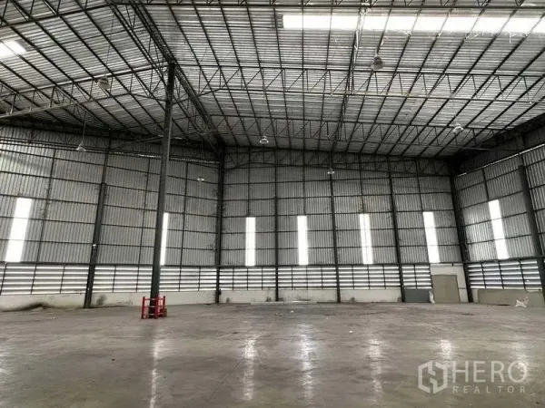 Warehouse for rent in Si Racha, Chon Buri - Spacious high-clearance warehouse interior with steel truss roof and polished concrete floor.