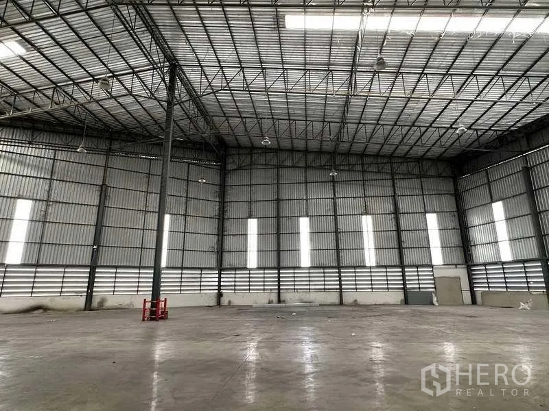 Warehouse for rent in Si Racha, Chon Buri - Spacious high-clearance warehouse interior with steel truss roof and polished concrete floor.