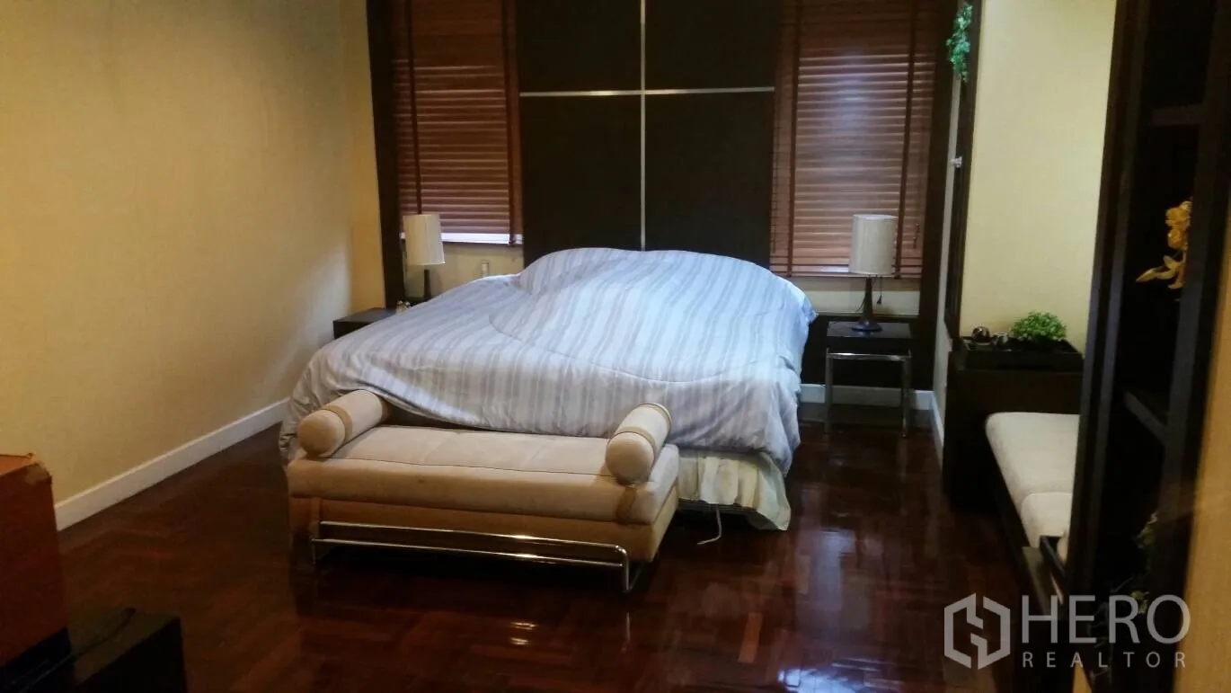 Detached House for rent in Lat Krabang, Bangkok - Master bedroom with large bed, bench seat, and polished wooden floors.
