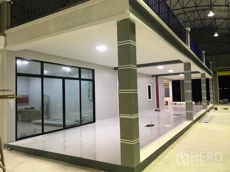 货栈 出租在Bang Pakong, Chachoengsao - 一层办公室区，推拉玻璃门与柱廊，位于夹层下方灯光明亮。
