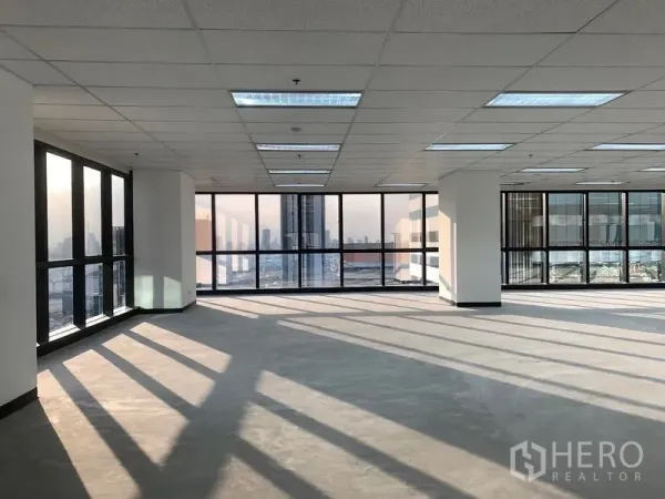 Office Space for rent in Din Daeng, Bangkok - Sunlit open‑plan office floor with floor‑to‑ceiling windows, grid‑ceiling lighting, and Bangkok skyline views.