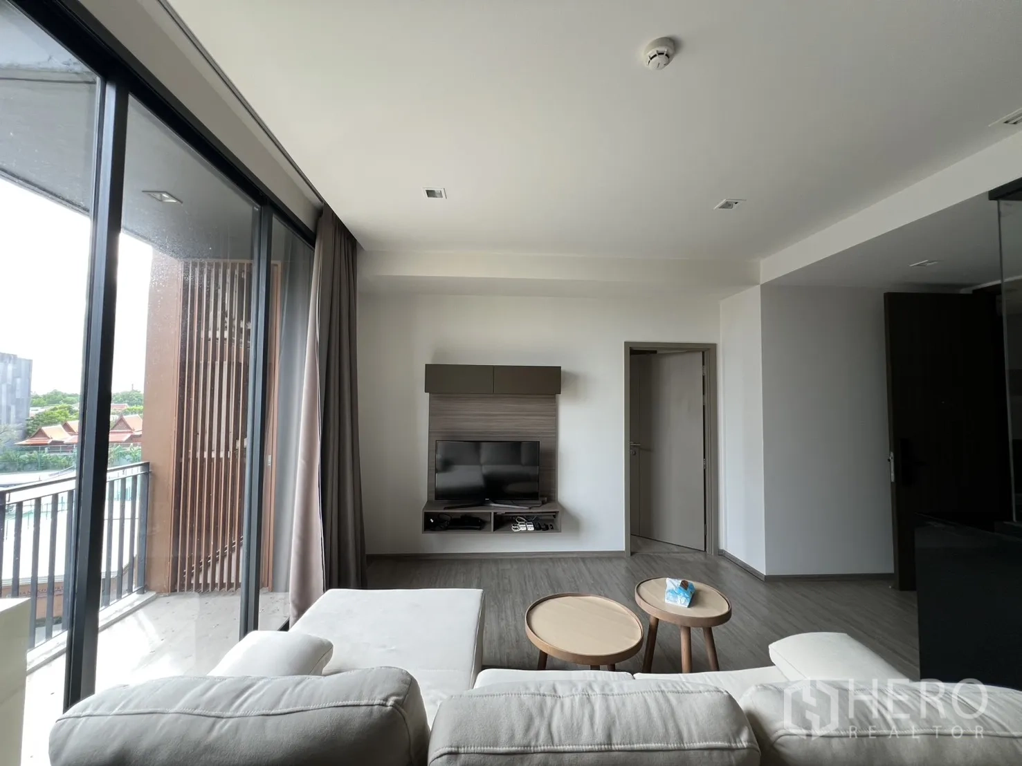 คอนโด for rent in Watthana, Bangkok - หน้าต่างสูงจากพื้นจรดเพดานเติมแสงให้ห้องนั่งเล่นที่มีโซฟามุมและโต๊ะข้าง.