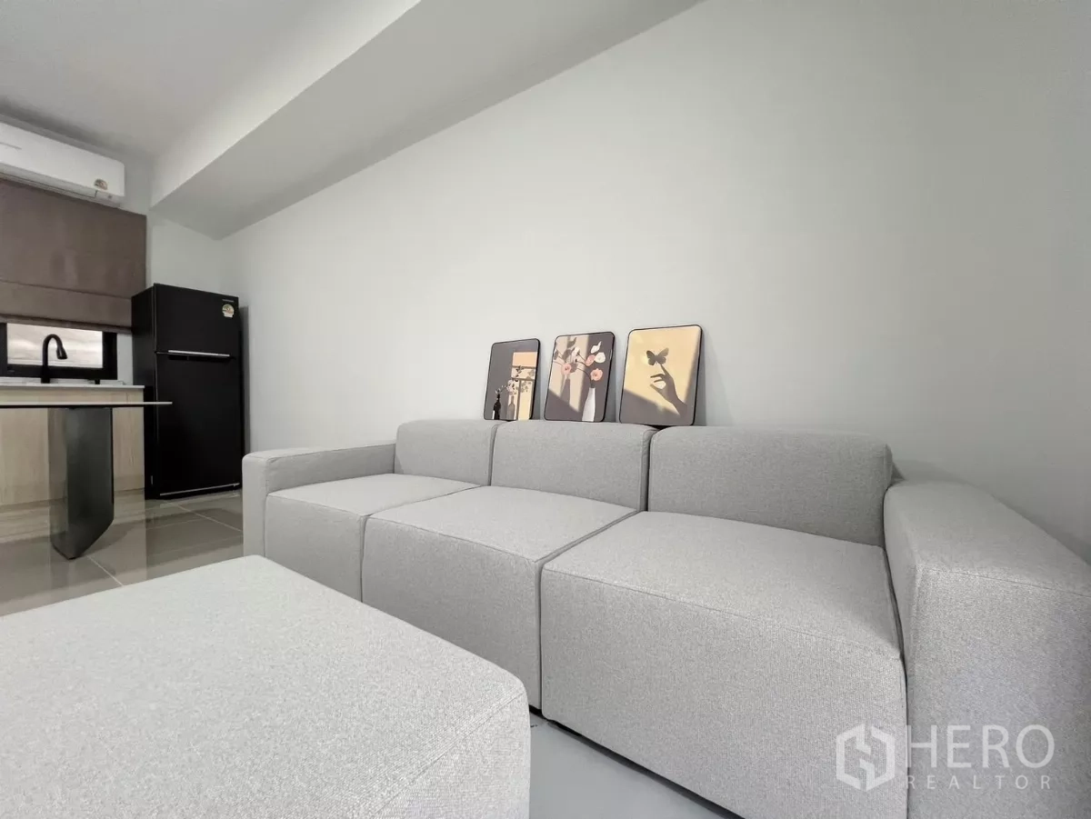 Townhouse for rent in Bang Phli, Samut Prakan - Cozy seating area with modular grey sofa beside a pantry and refrigerator.