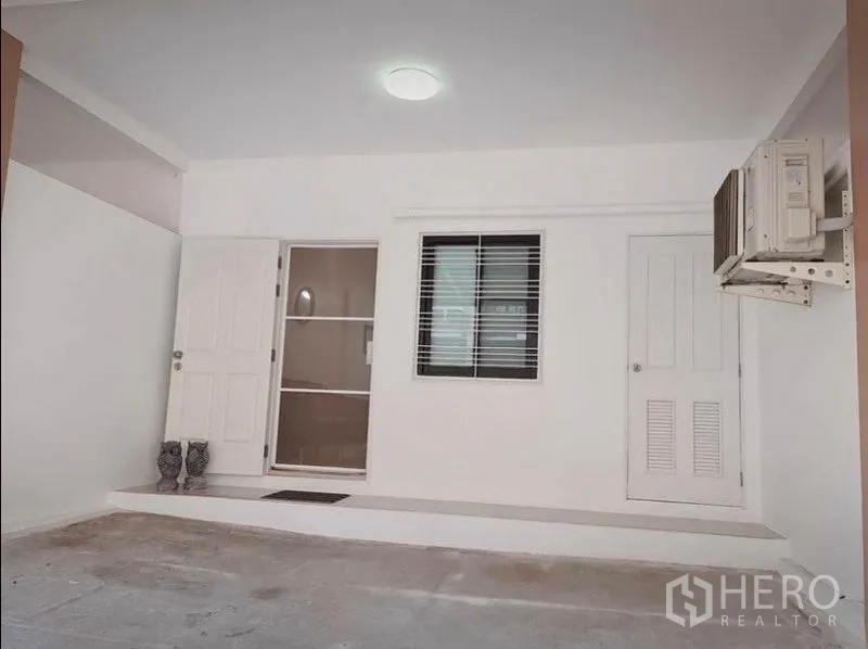 Townhouse for rent in Suan Luang, Bangkok - Close view of covered carport and main entrance with white doors and window