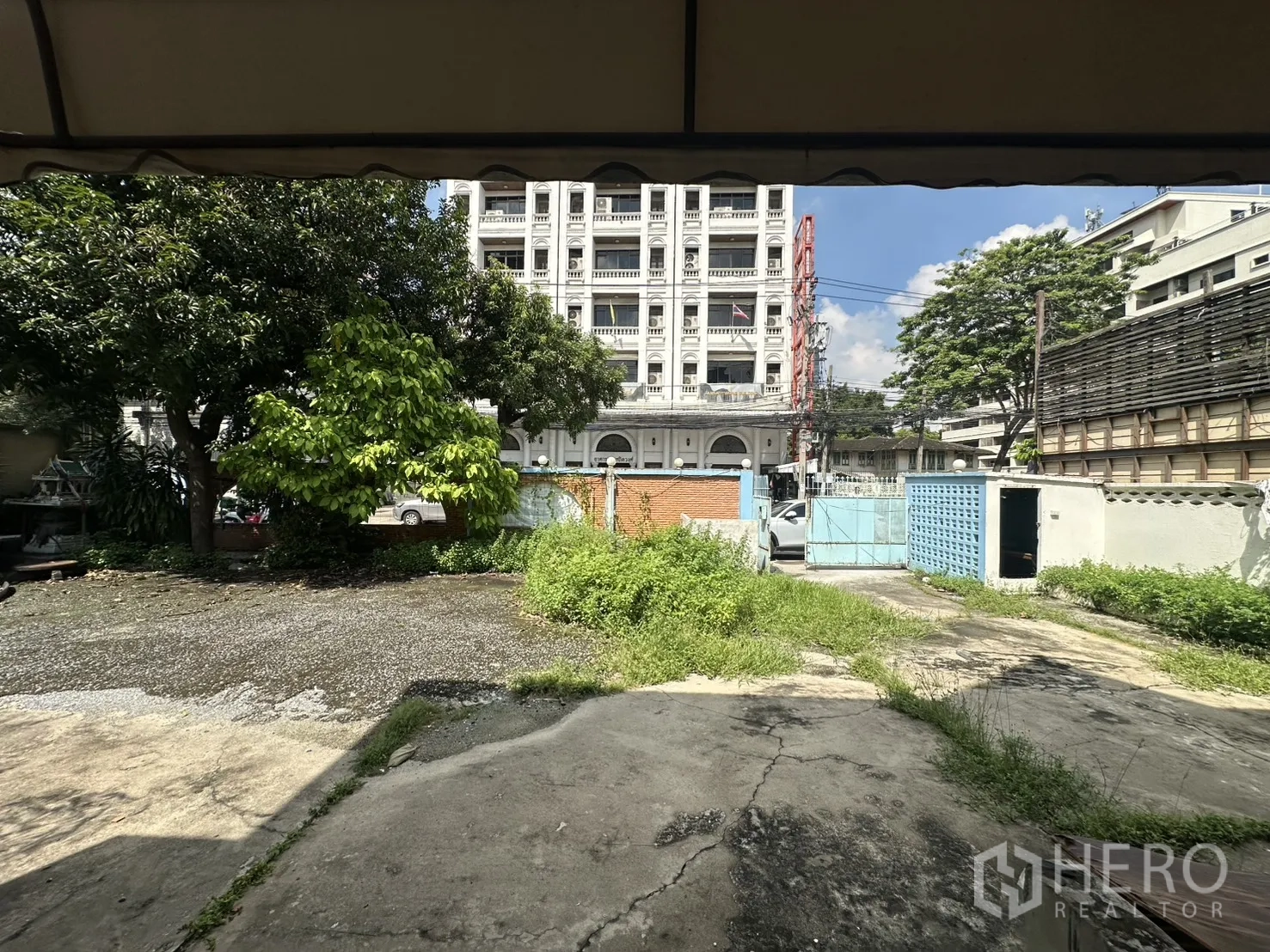 独栋房屋 for rent in Watthana, Bangkok - 从门廊望向庭院与大门，树木环绕、前场开阔。