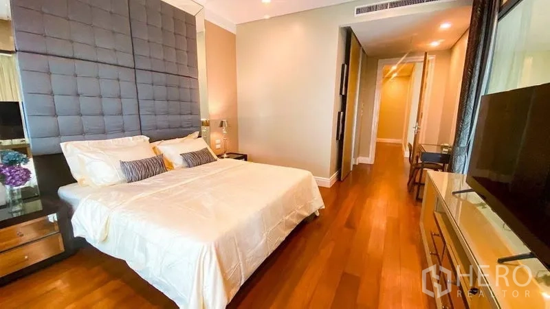 Condominium for rent in Khlong Toei, Bangkok - Master bedroom featuring a padded headboard, warm wood floors and a TV console.