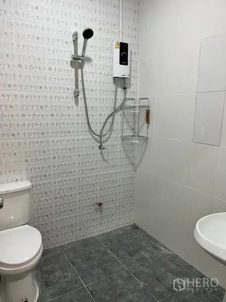 Townhouse for rent in Din Daeng, Bangkok - Tiled bathroom featuring a shower with water heater, toilet, and wall-mounted sink.