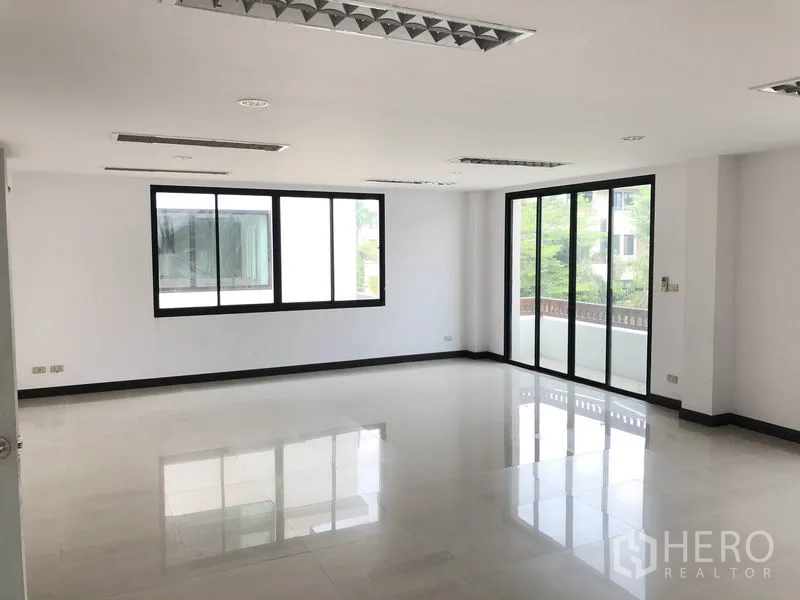 带办公室的家 出租在Wang Thonglang, Bangkok - 采光充足的开放式办公层，白色地砖、嵌入式灯，推拉玻璃门连接阳台。