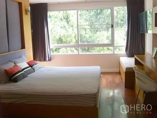 Condominium for rent in Watthana, Bangkok - Master bedroom with a large window, leafy views and a built-in desk.