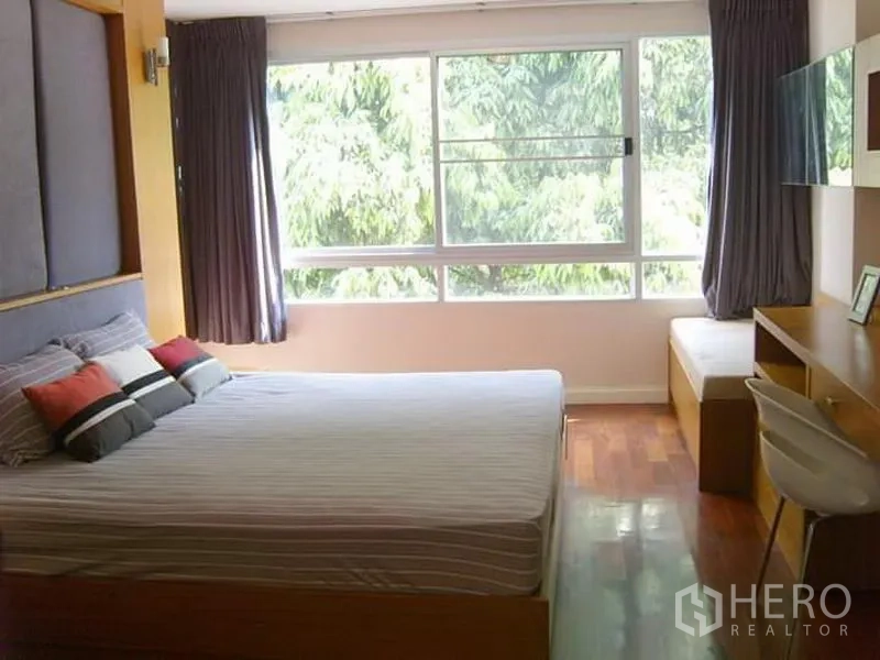 Condominium for rent in Watthana, Bangkok - Master bedroom with a large window, leafy views and a built-in desk.