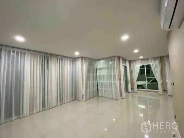 独立式住宅 出租在Prawet, Bangkok - 明亮客厅，亮面瓷砖地面、纱帘与嵌入式筒灯，空间通透。