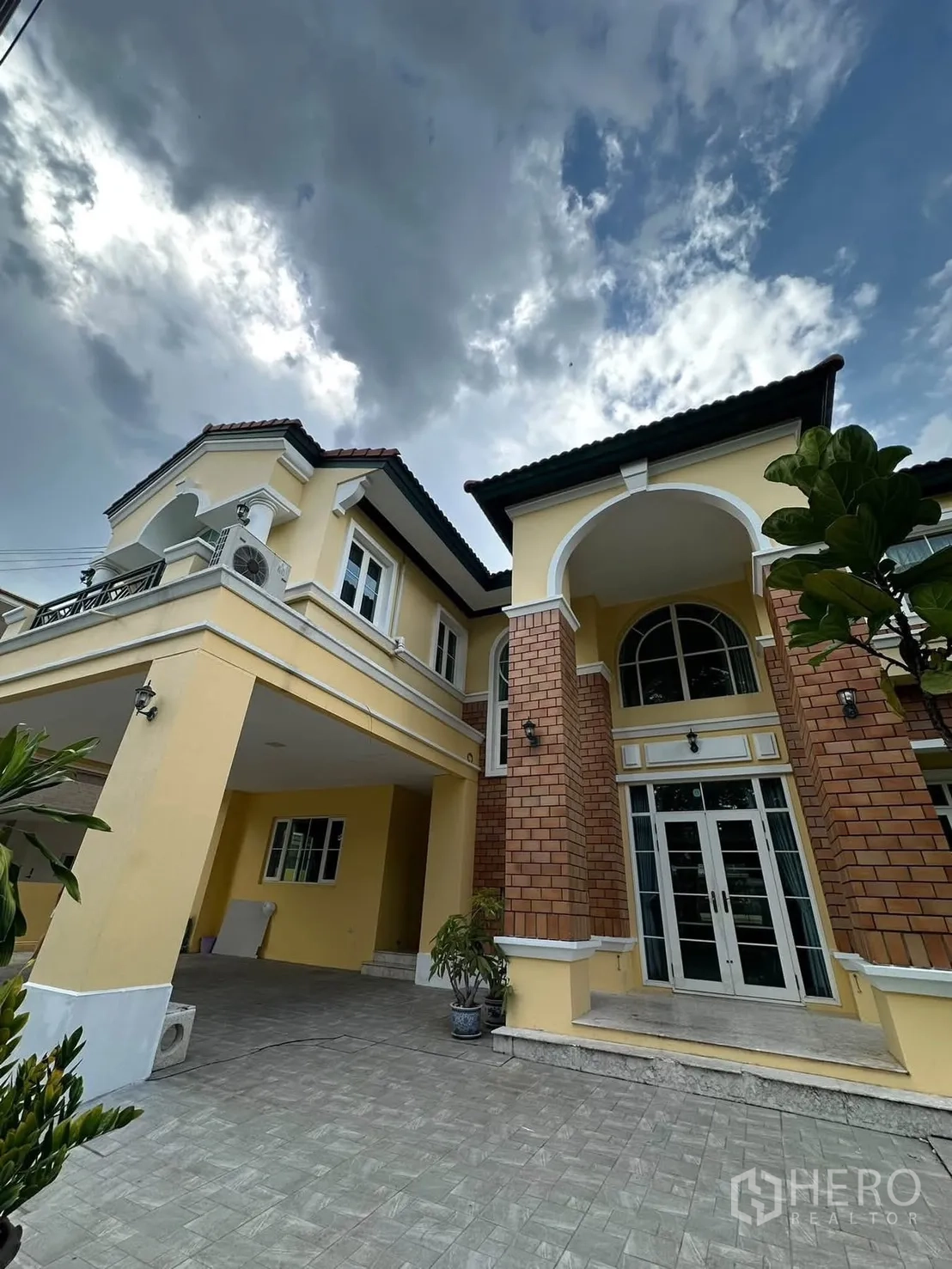 Detached House for rent in Phra Khanong, Bangkok - Entry porch with arched columns, carport, paved driveway, and tall French doors.