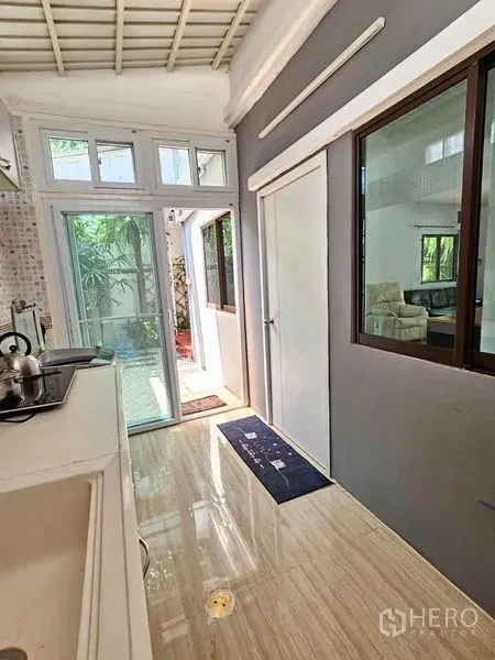 Townhouse for rent - Light-filled utility corridor with sliding glass doors opening to the side garden.