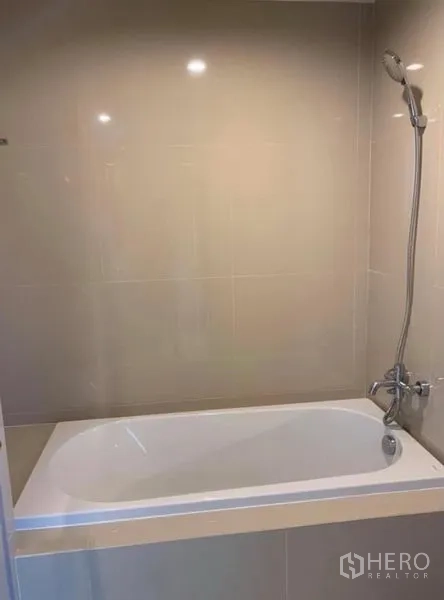 公寓 出租在Pathum Wan, Bangkok - 瓷砖浴室，设有浴缸与手持花洒。